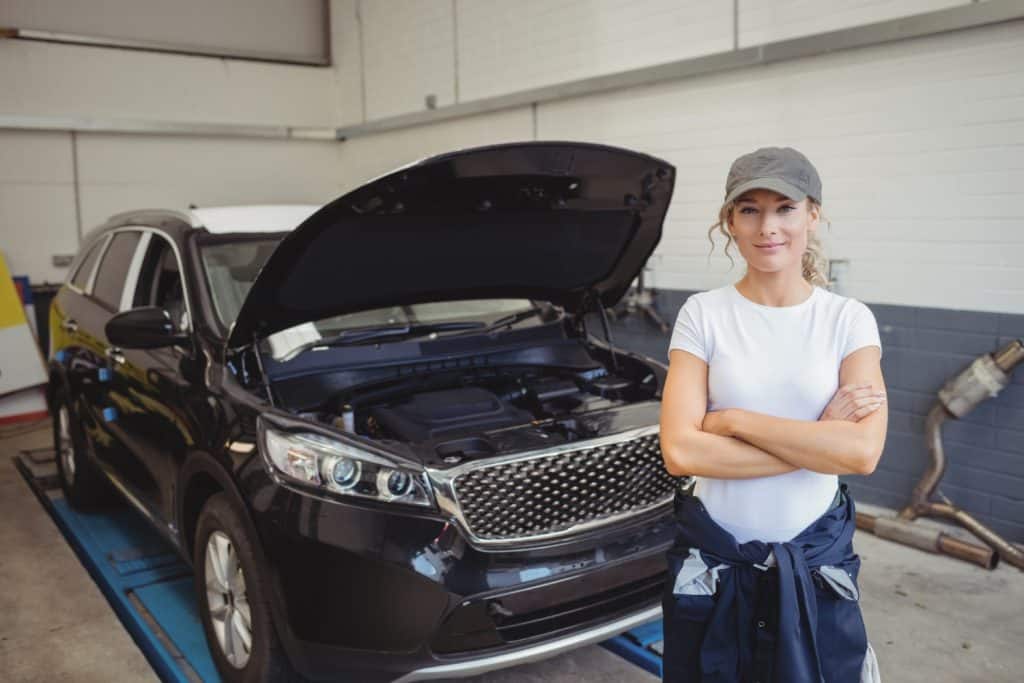 Woman standing beside open car hood.